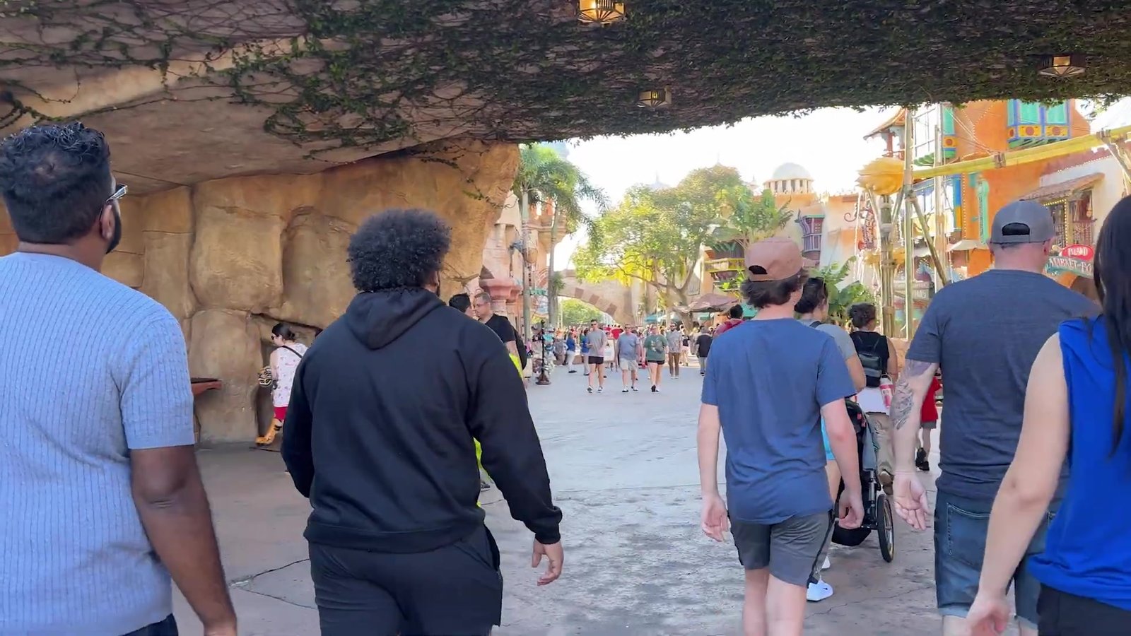 Visitantes passando pelo arco de pedra do Port of Entry, a entrada do Islands of Adventure, no fim da tarde
