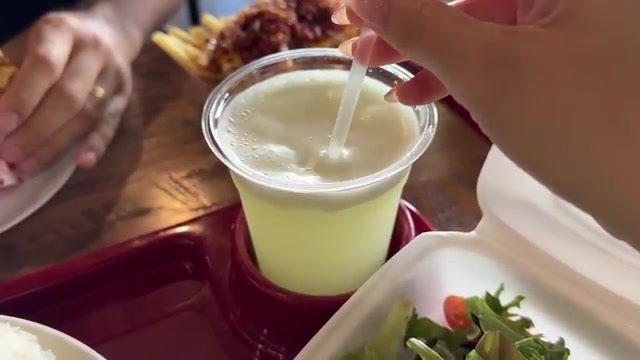 Copo de limonada gelada da Cantina Brazil com canudo, ao lado de uma marmita com salada