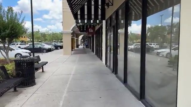 Corredor coberto do Lake Buena Vista Factory Stores, com bancos e o estacionamento colado nas lojas