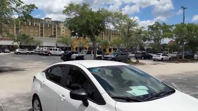 Estacionamento do Lake Buena Vista Factory Stores com carros parados em frente às lojas e hotéis ao fundo