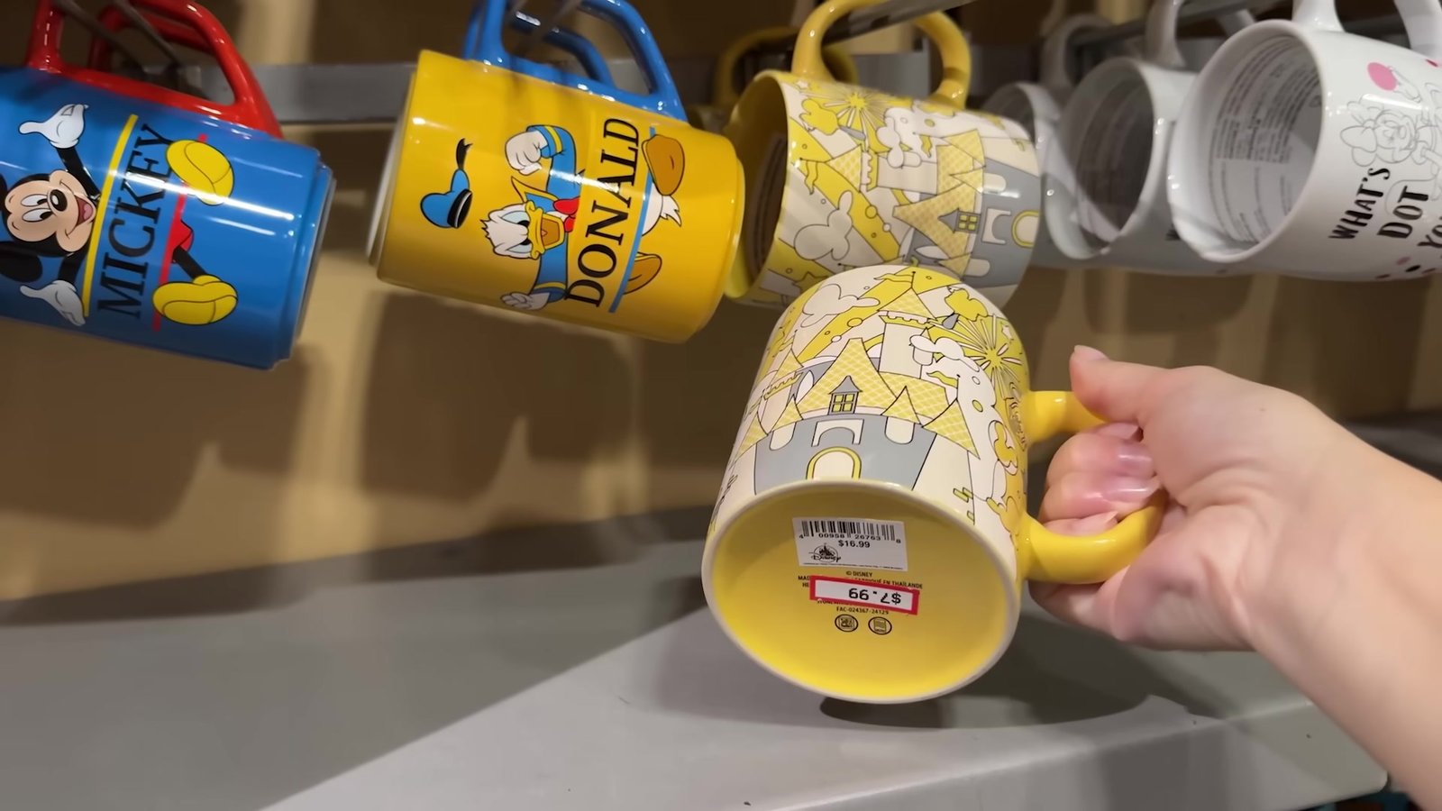 Canecas do Mickey, do Donald e do castelo na prateleira do outlet da Disney