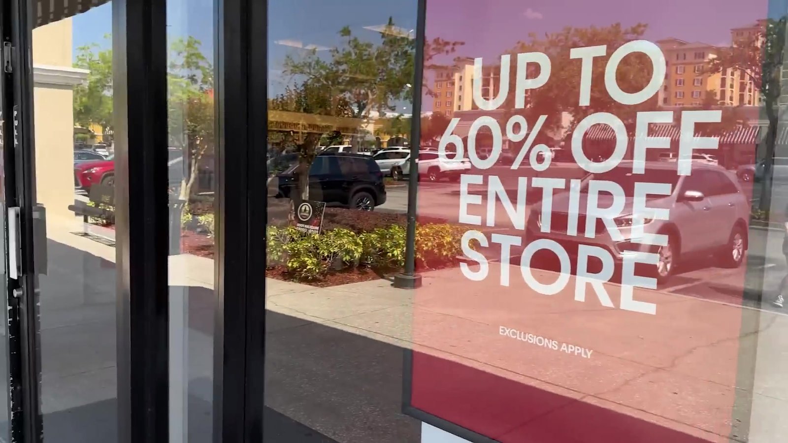 Cartaz de "Up to 60% off entire store" na vitrine de uma loja do outlet Lake Buena Vista