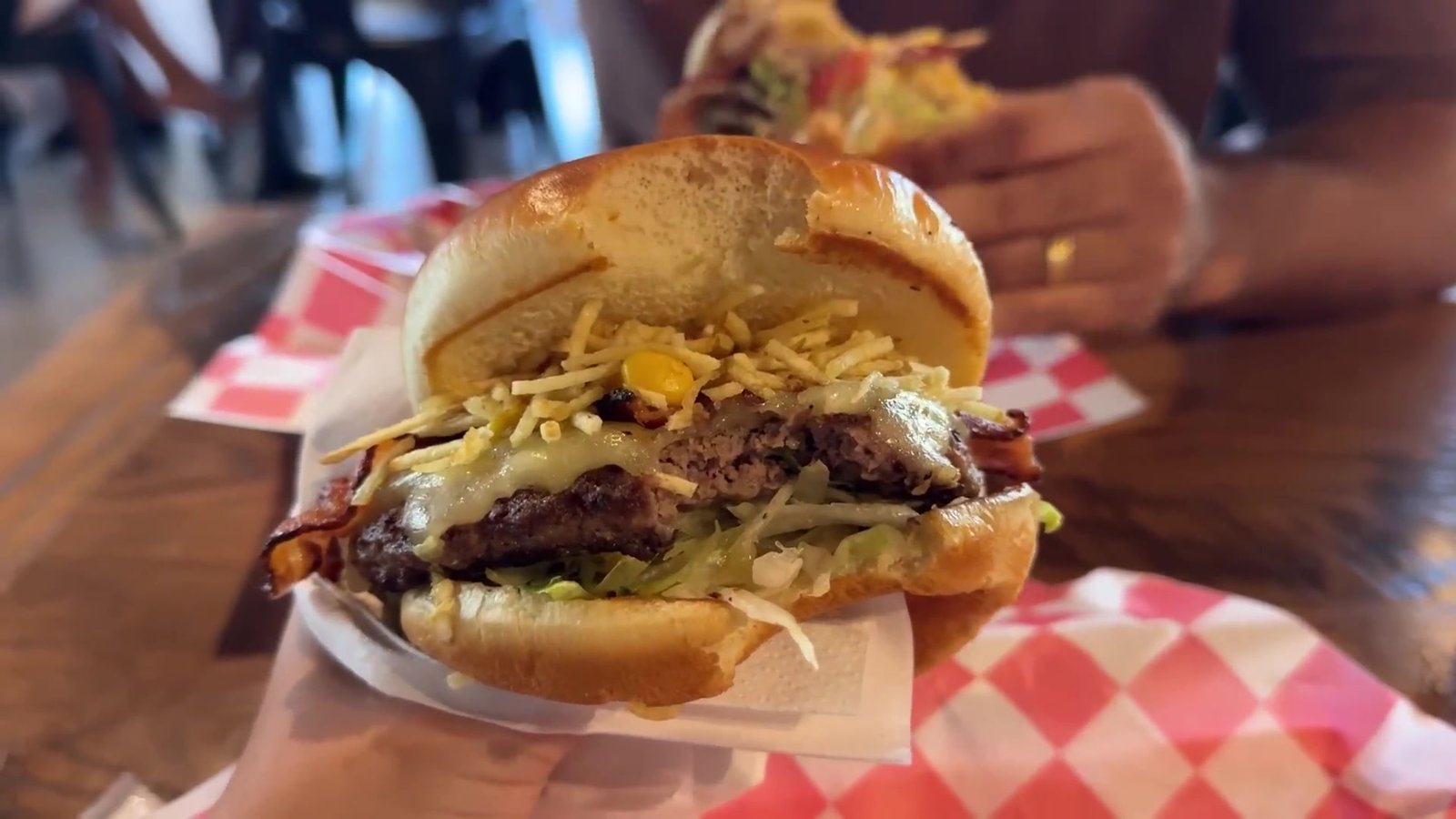 Hambúrguer com batata palha, alface e queijo na mão, na antiga hamburgueria da praça de alimentação do outlet