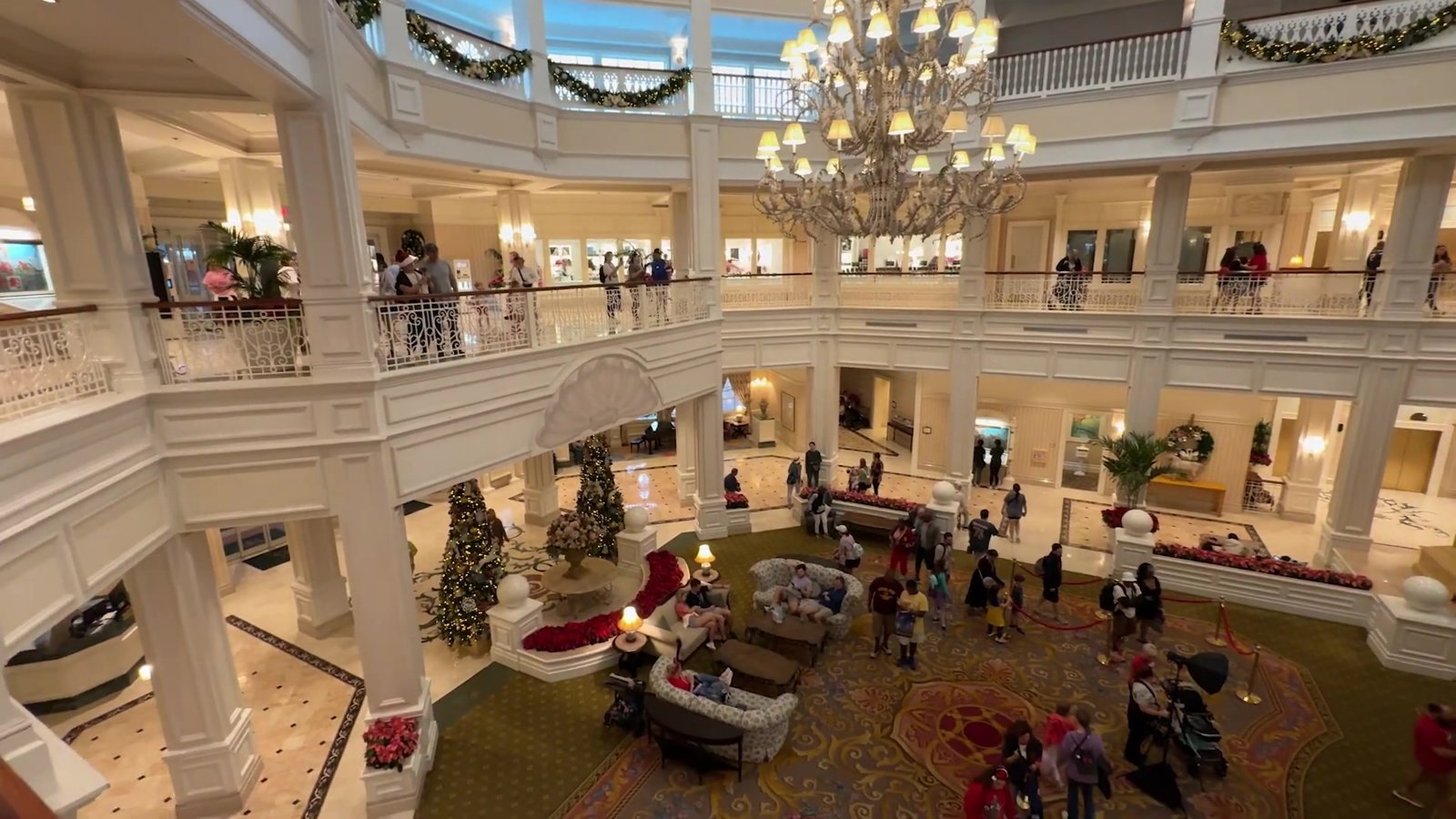 Lobby do Grand Floridian com lustre gigante, varandas internas e árvores de Natal