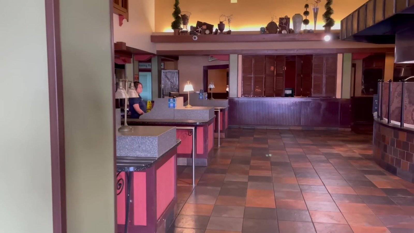 Interior vazio de um dos restaurantes do SeaWorld, com balcões rosa e mesas de madeira