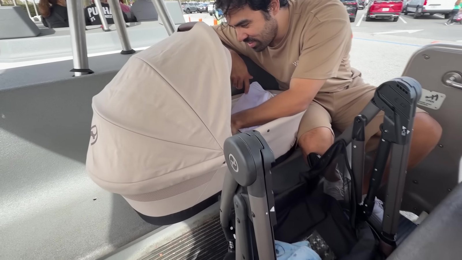 Gustavo ajeitando o carrinho de bebê dentro do tram do estacionamento do Magic Kingdom
