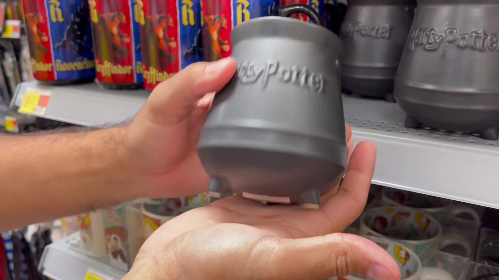 Caneca em formato de caldeirão do Harry Potter na mão, no corredor do Walmart de Orlando