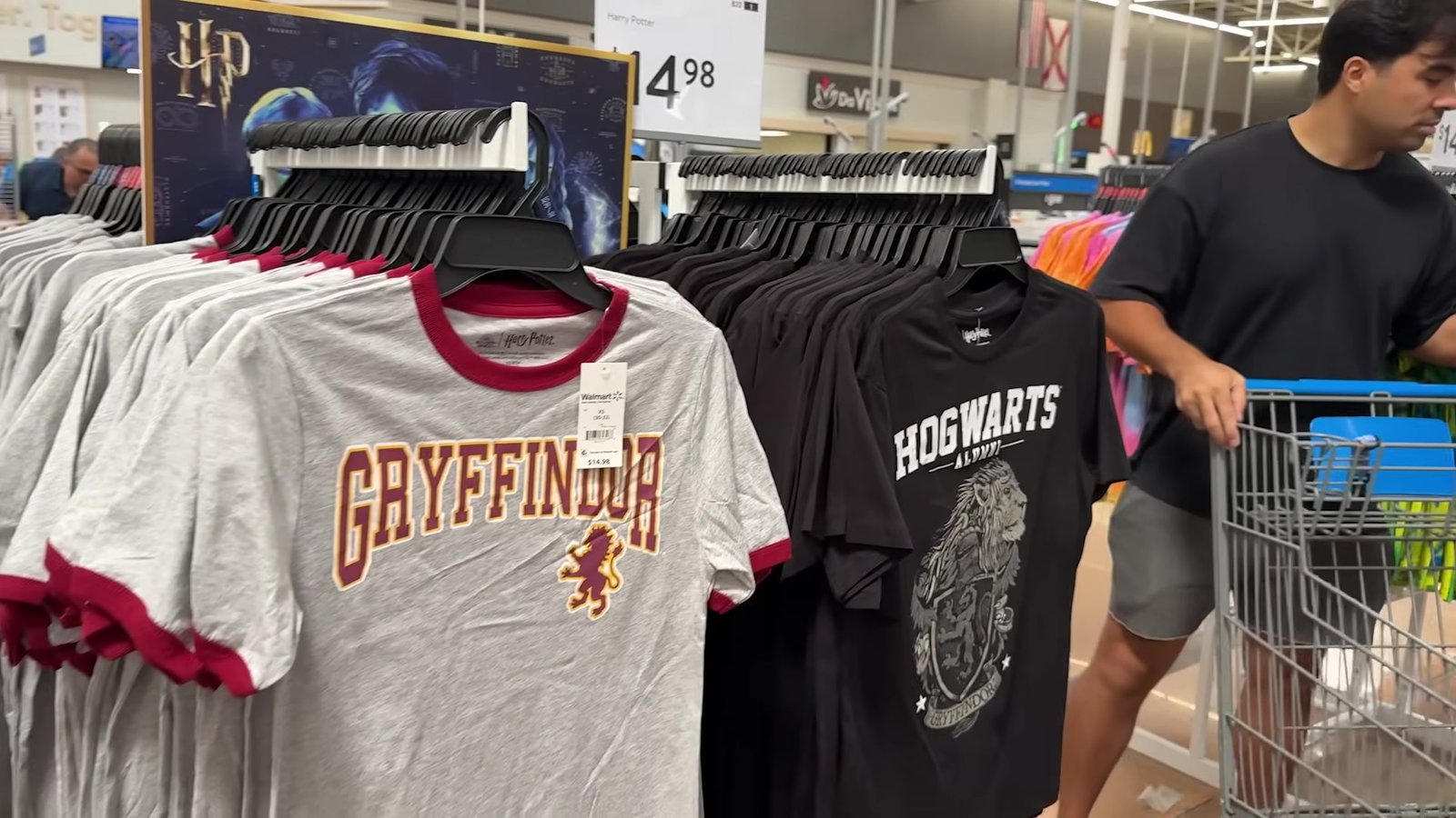Araras com camisetas da Grifinória e de Hogwarts no corredor de Harry Potter do Walmart
