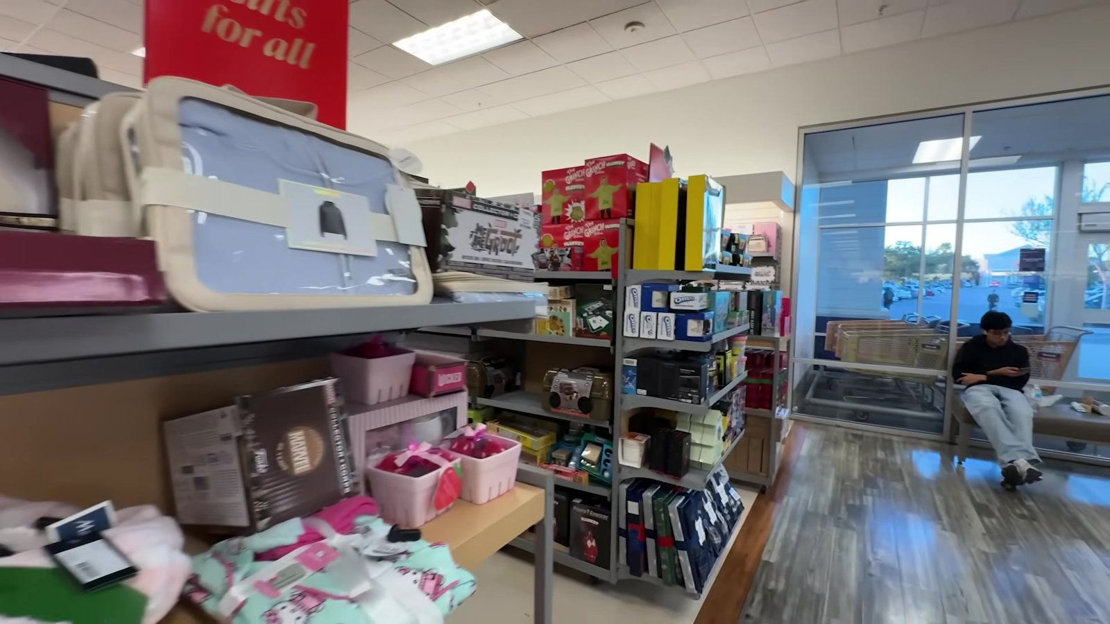 Prateleiras de kits de presente de Natal logo na entrada da Marshalls, com a placa Gifts for All