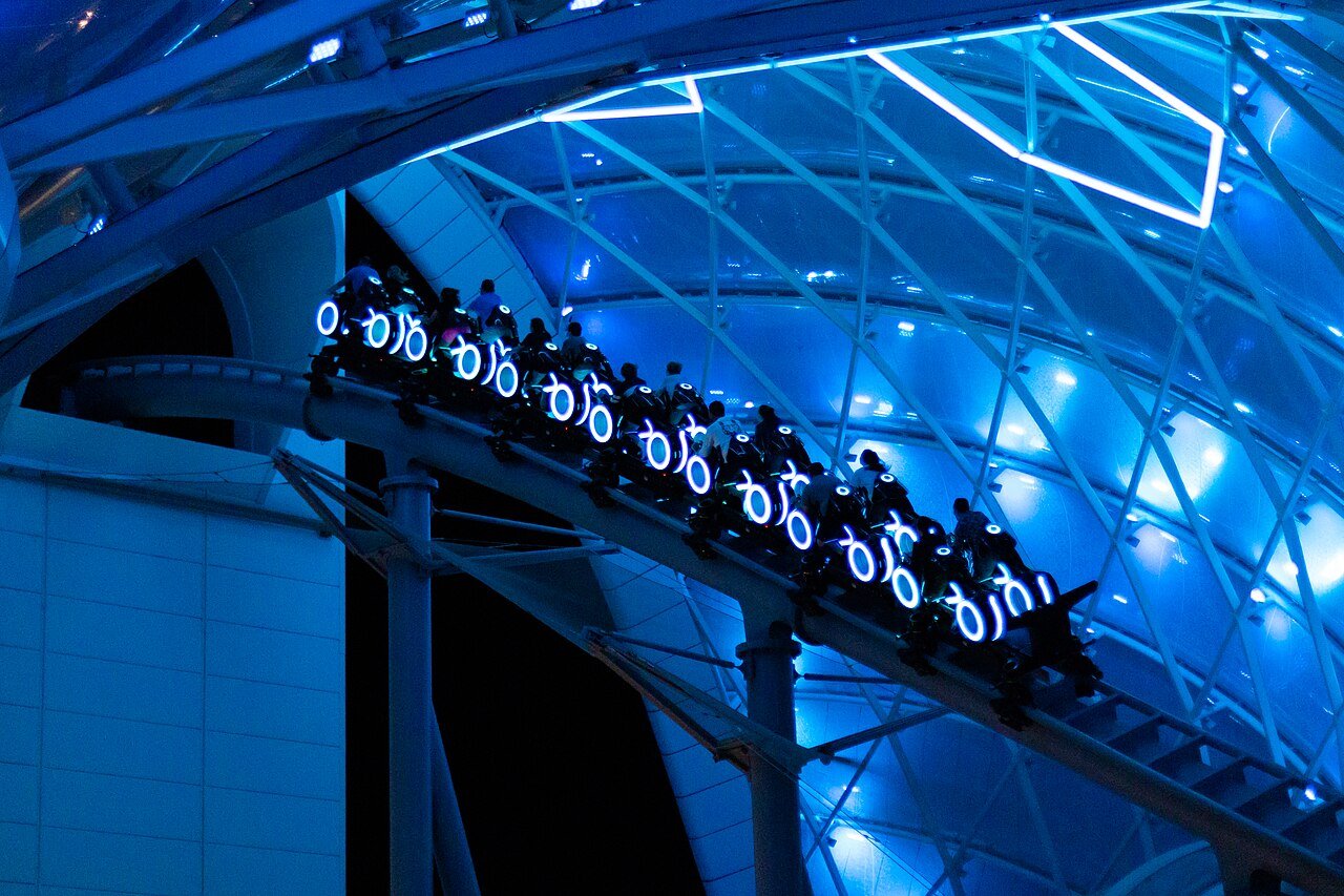 Trens da TRON Lightcycle Run correndo à noite sob o domo azul do Magic Kingdom