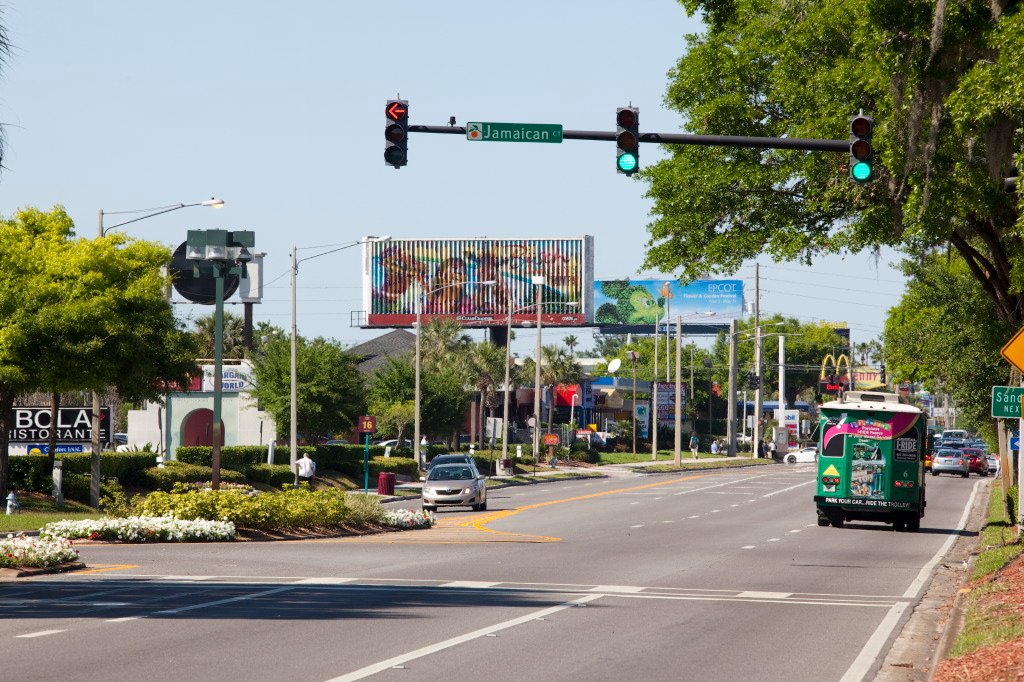 Avenida International Drive em Orlando, com semáforo, outdoor e o ônibus I-Ride Trolley