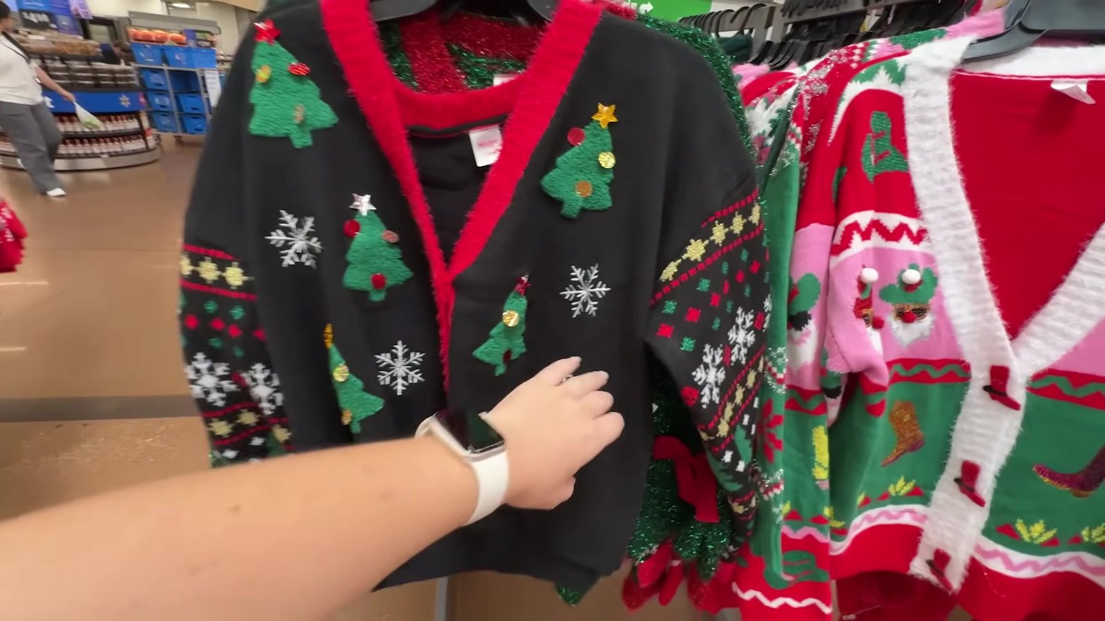 Cardigã preto de Natal com árvores bordadas e detalhes vermelhos na arara da TJ Maxx