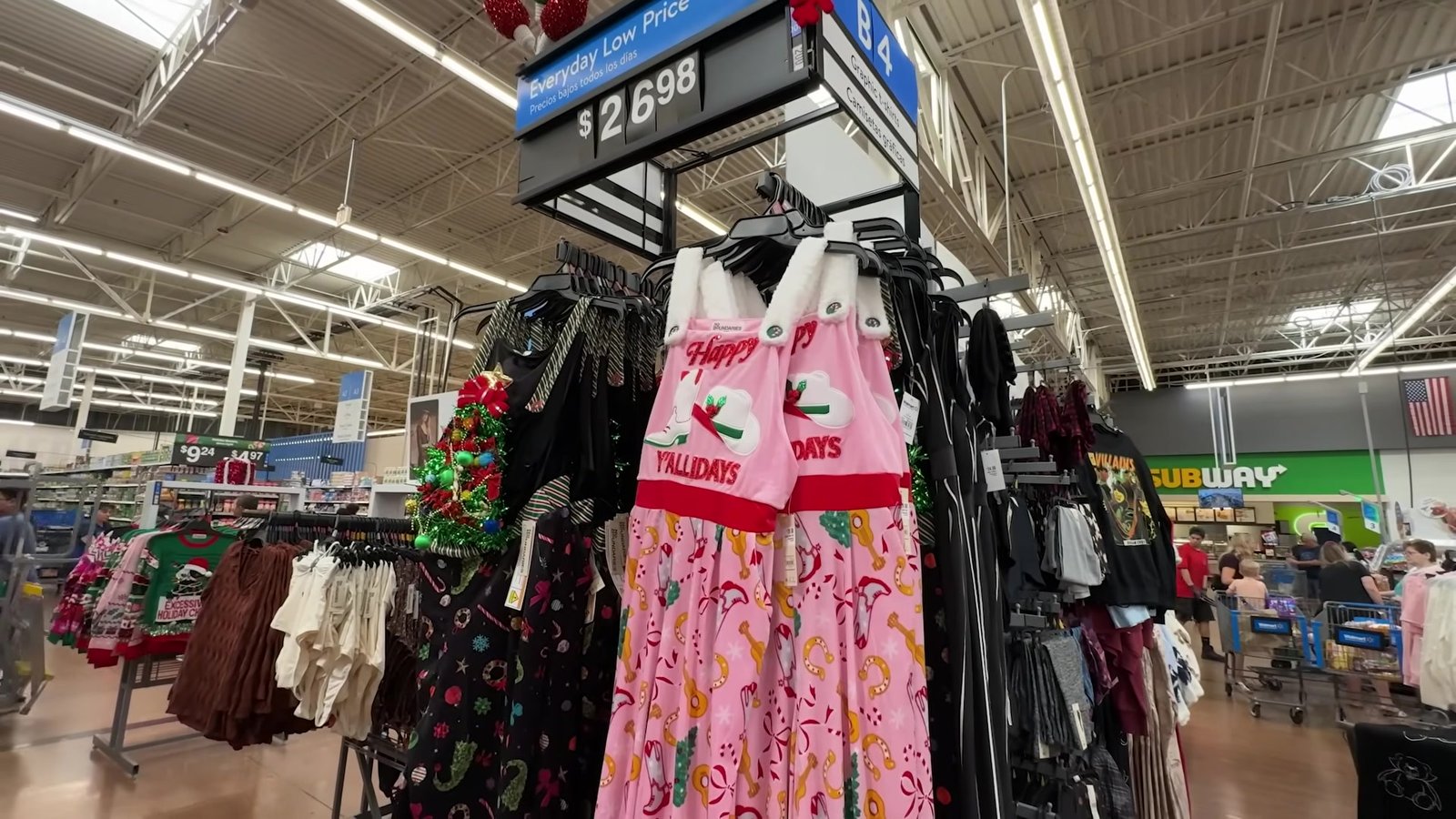 Vestido rosa Happy Holidays e camisetas natalinas numa arara do Walmart com etiqueta de US$ 26,98