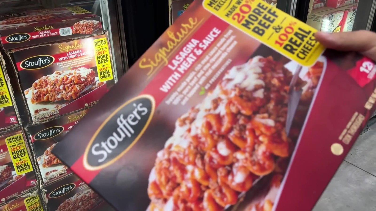 Caixa de lasanha Stouffer's tamanho família na mão, no corredor de congelados do Sam's Club