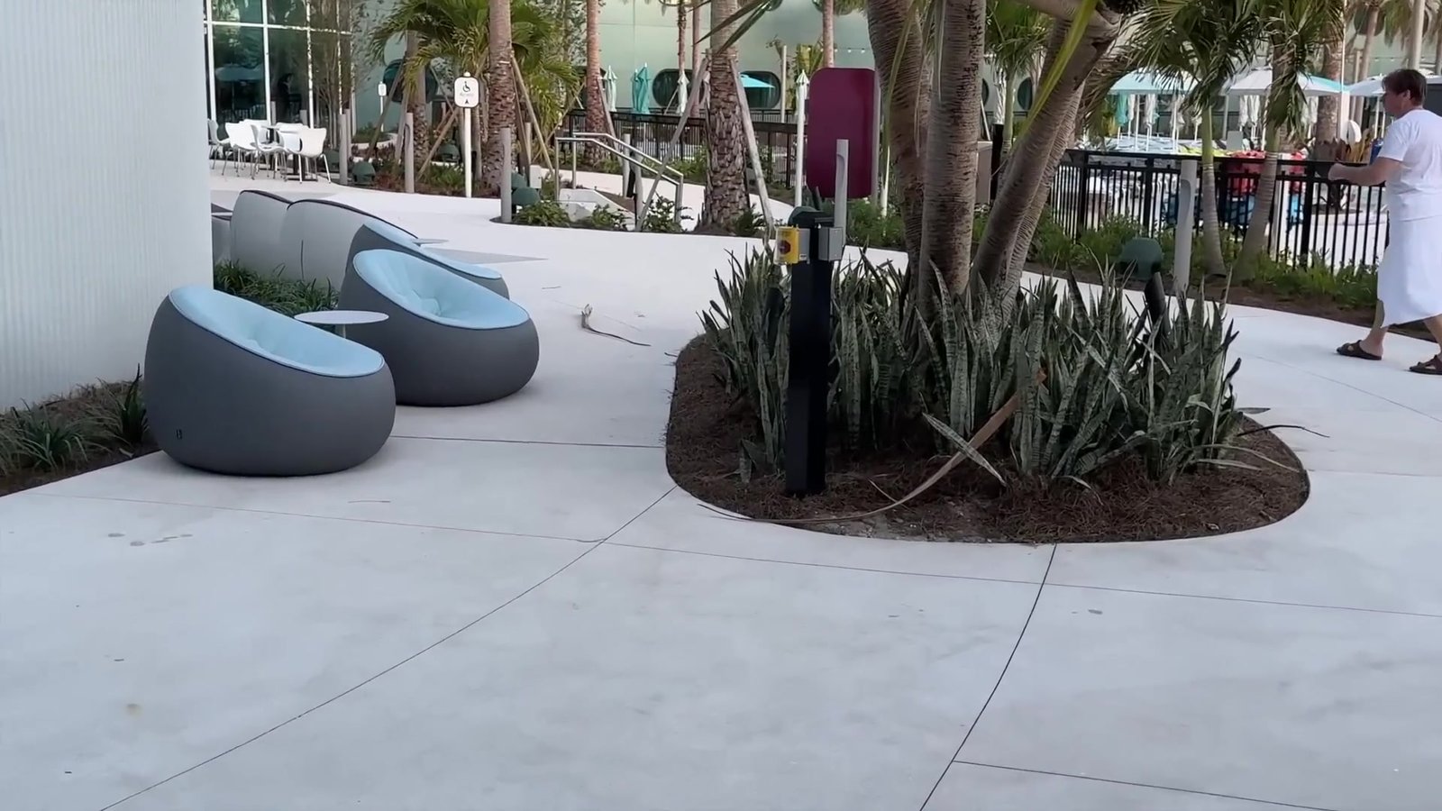 Área externa do Terra Luna com poltronas redondas e palmeiras ao lado da piscina
