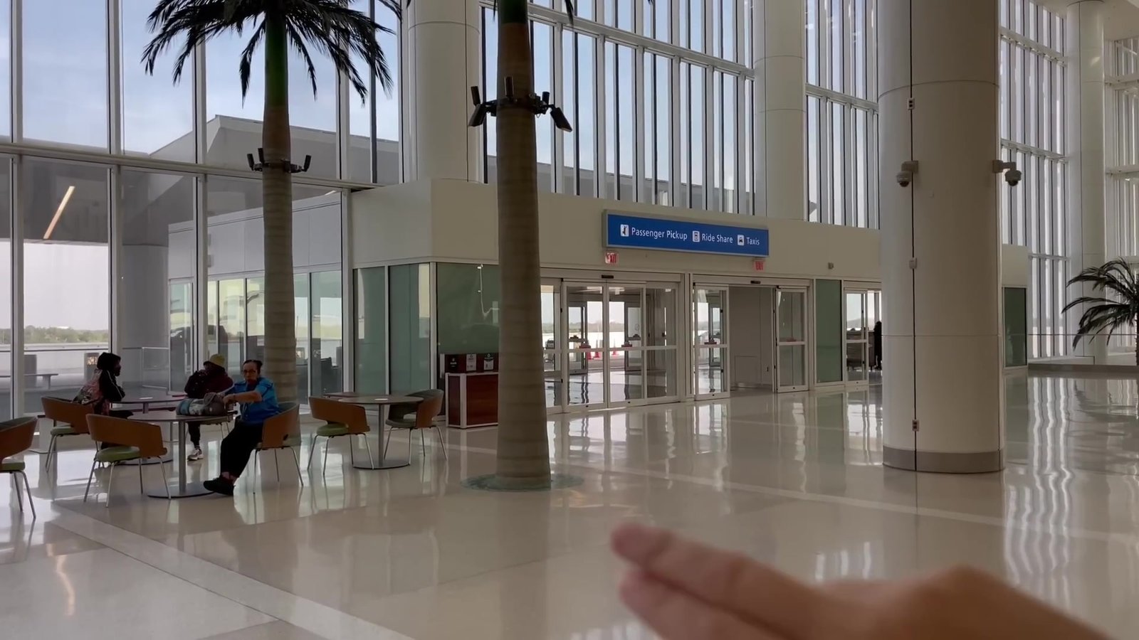 Saguão de entrada do Terminal C com palmeiras e pessoas sentadas