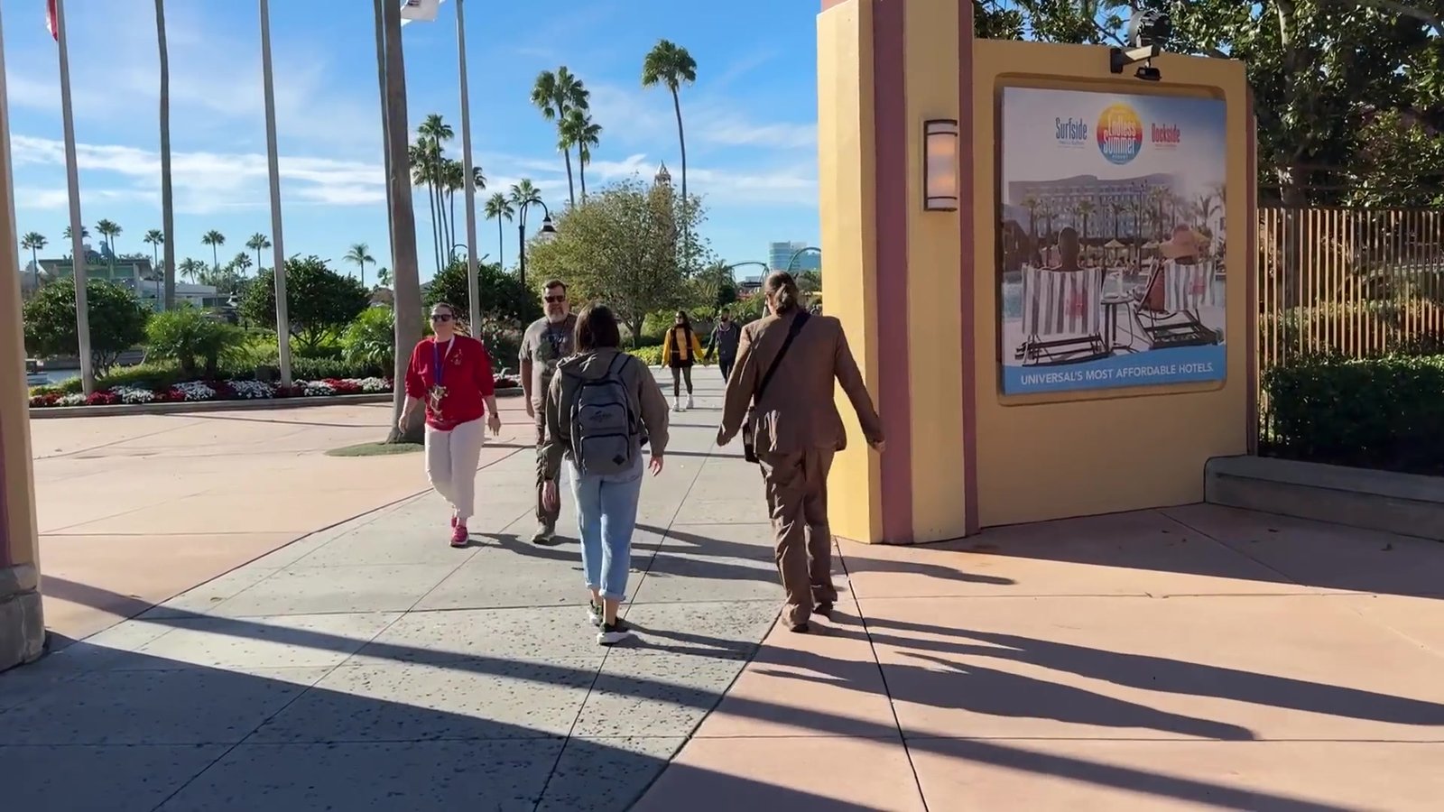 Visitantes caminhando pela entrada do Universal Studios em dia de sol