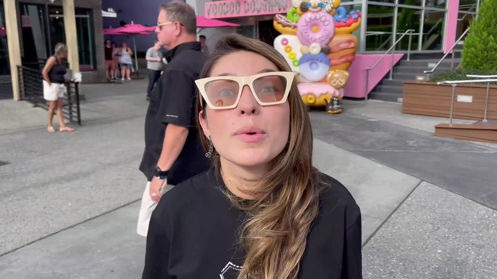 Gabi em frente à Voodoo Doughnut no CityWalk explicando a temática da loja