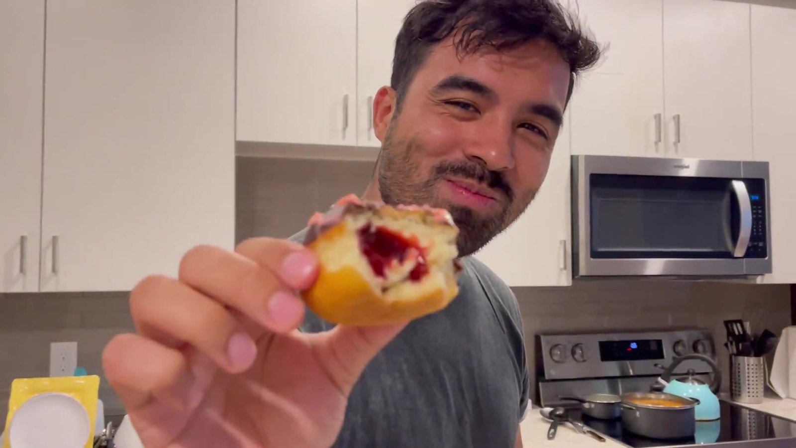 Gustavo mostrando um donut recheado de geleia vermelha mordido