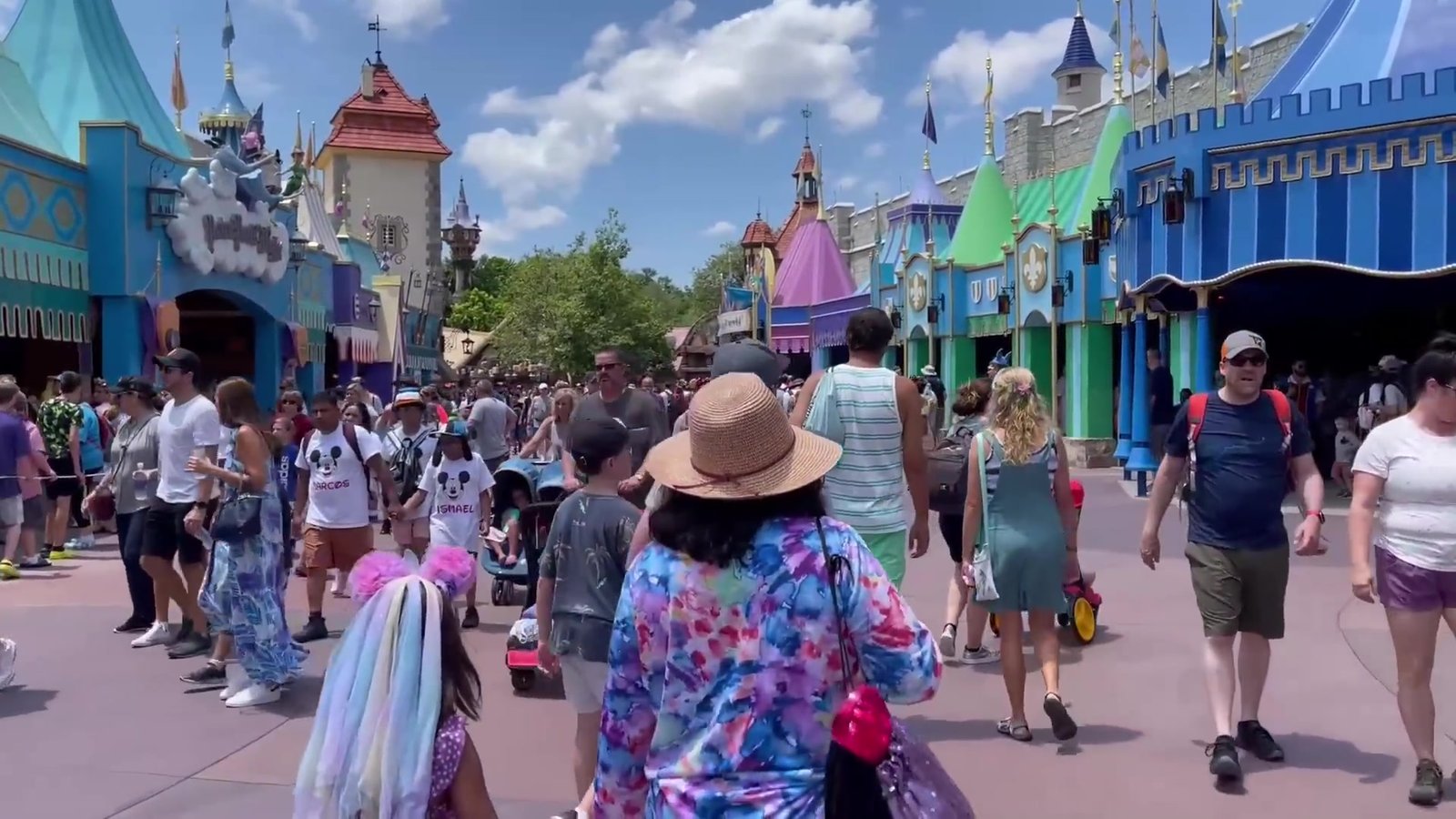 Rua movimentada da Fantasyland com as fachadas coloridas do Magic Kingdom