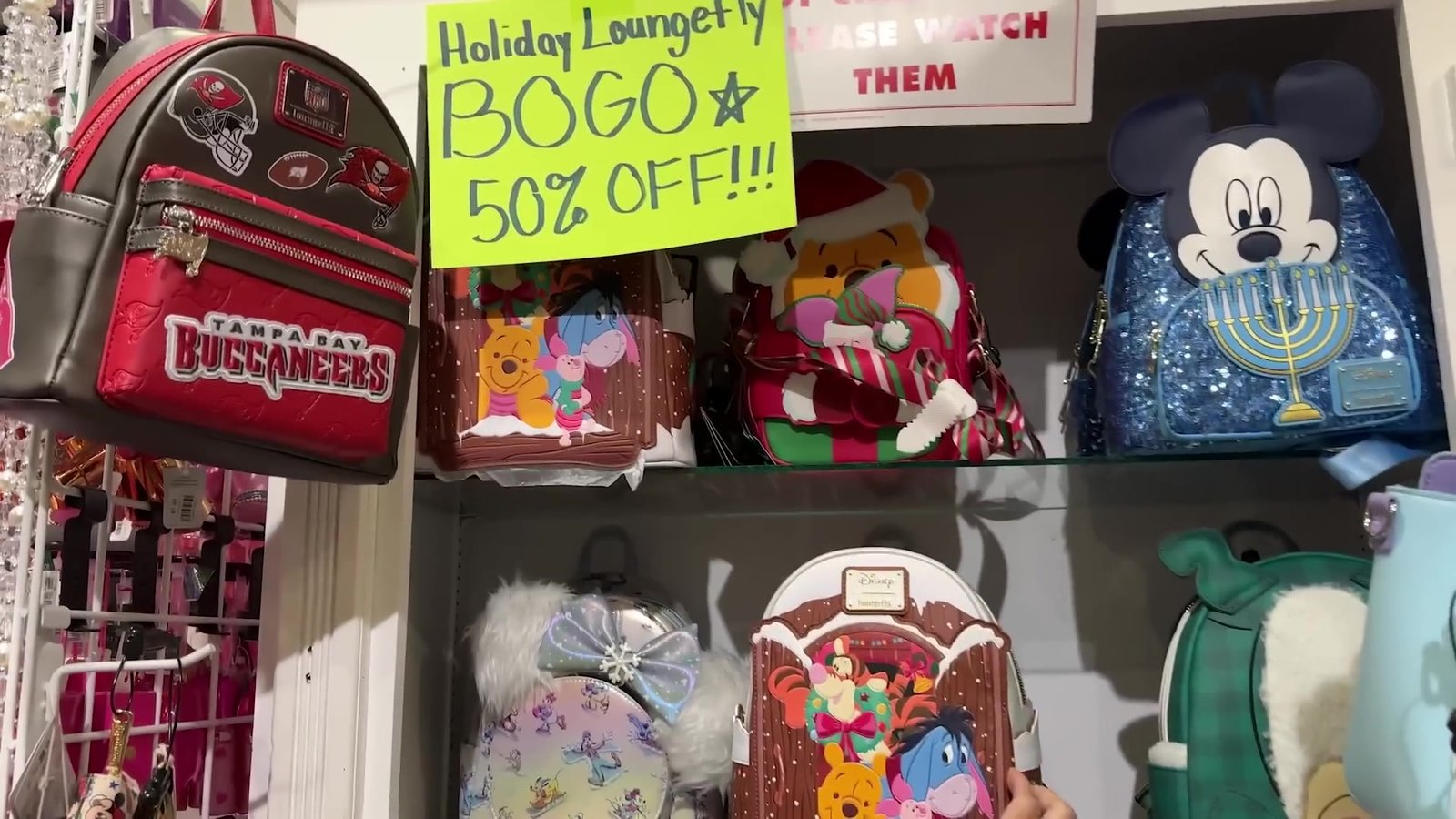 Prateleira de mochilas Loungefly de Natal com placa de promoção leve dois e pague metade no segundo