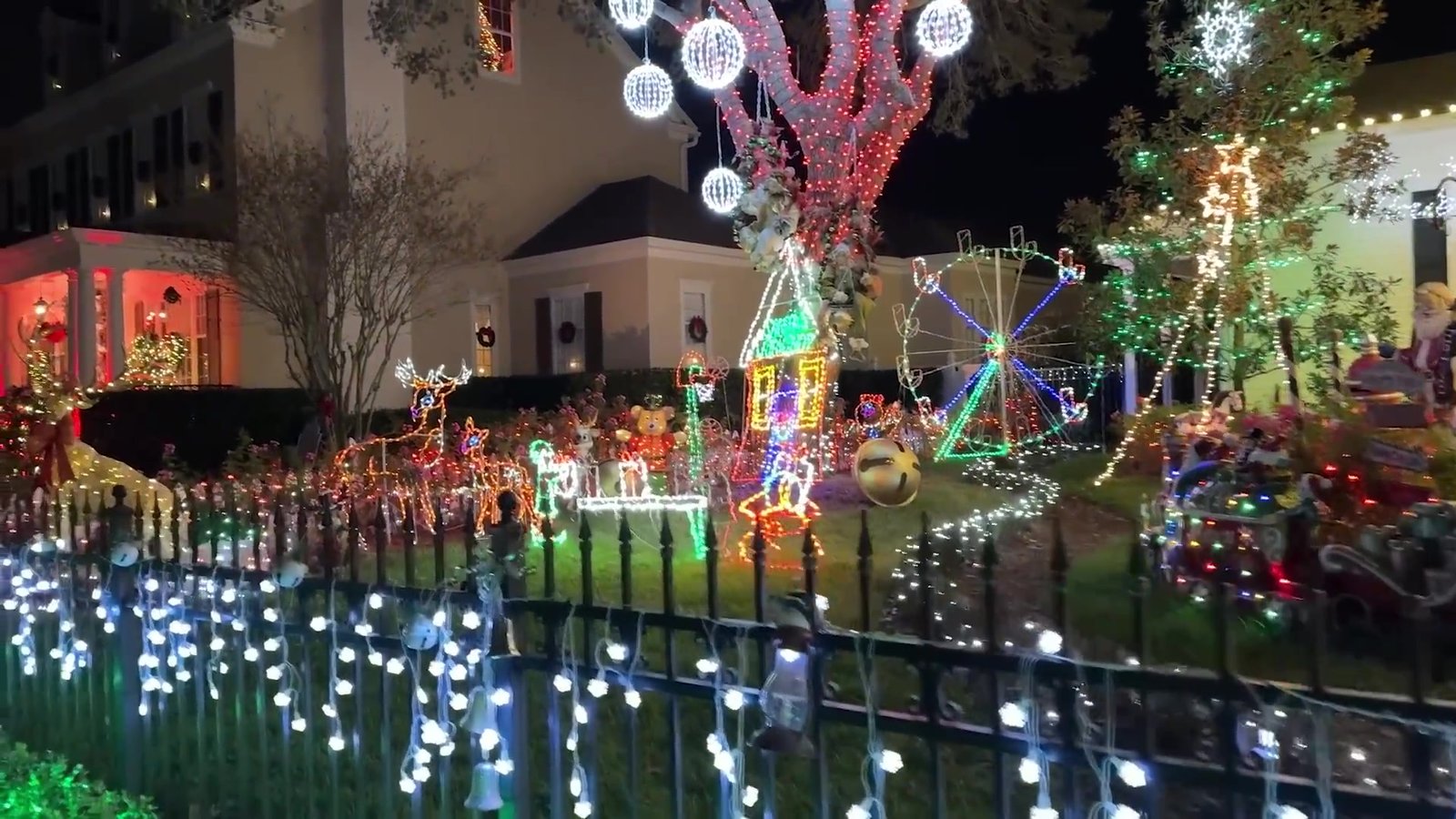 Jardim com árvore iluminada, carrossel de luzes e roda-gigante ao fundo em Celebration