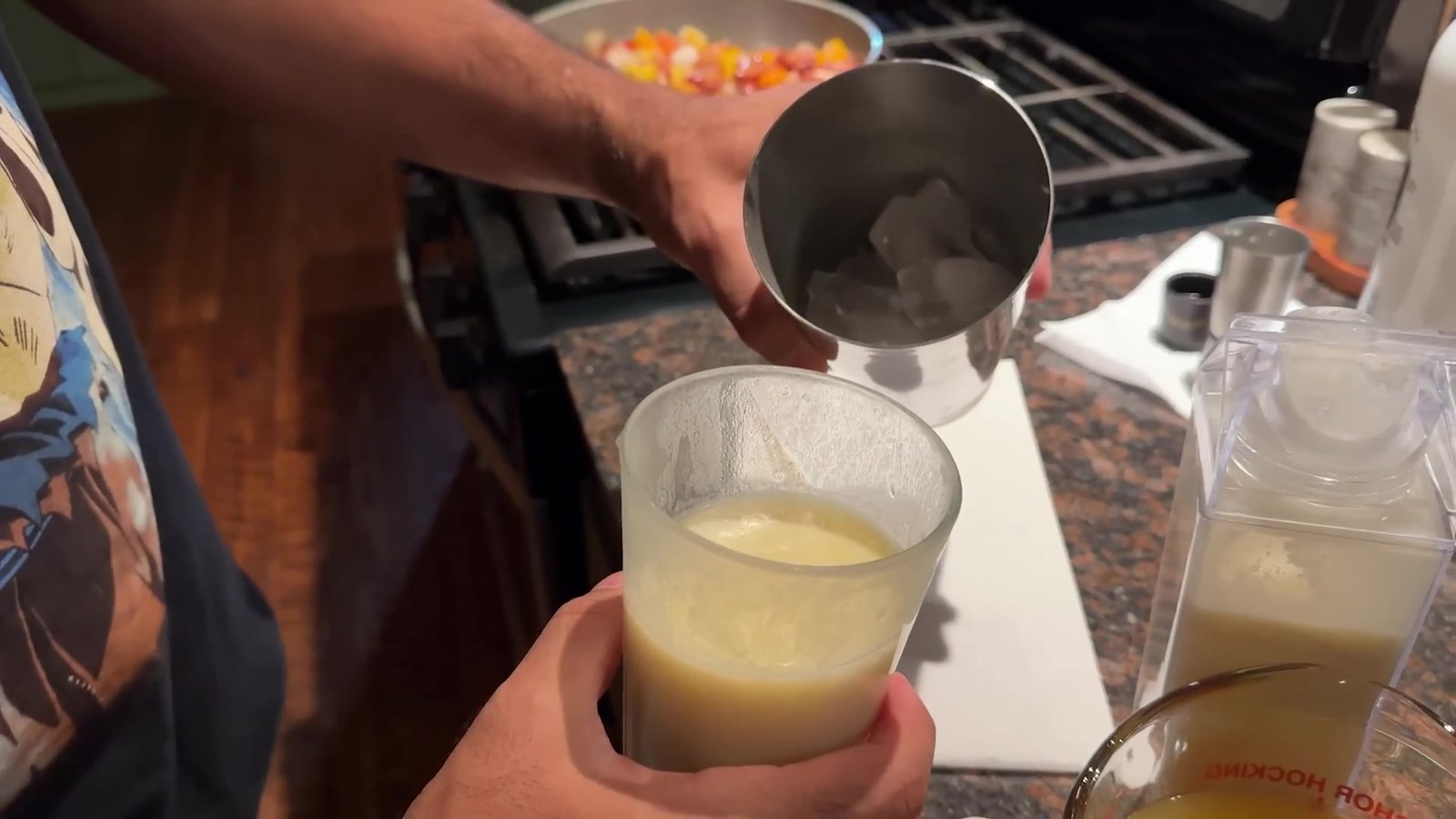 Gustavo servindo a pina colada cremosa num copo na cozinha da cabana